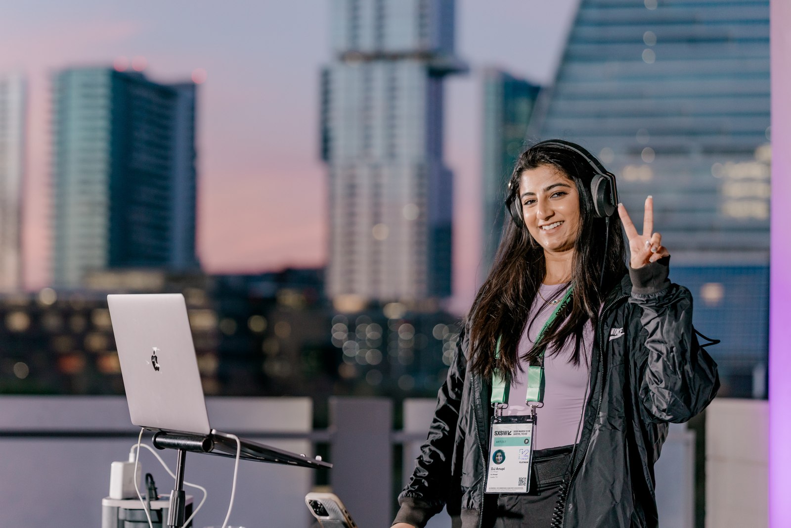 A rooftop DJ with the Austin skyline at dusk.