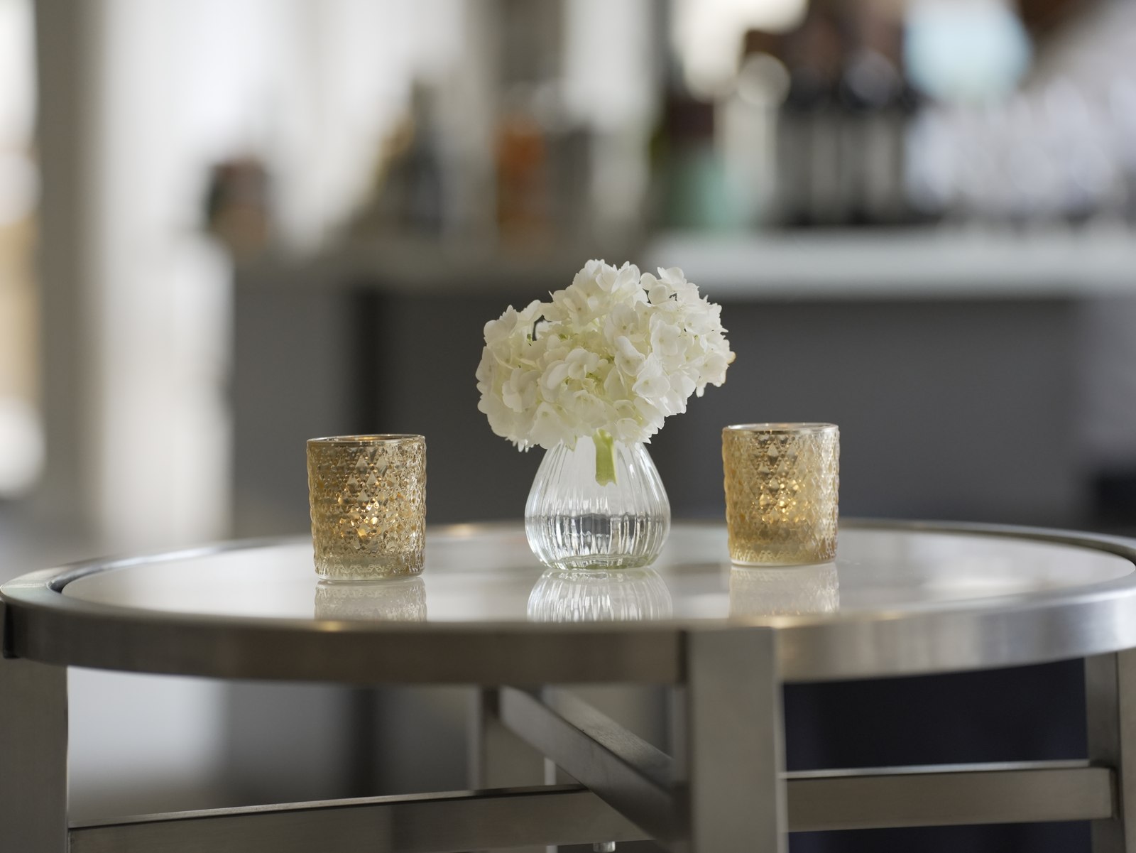 White hydrangeas and gold candle holders arranged on a cocktail table.